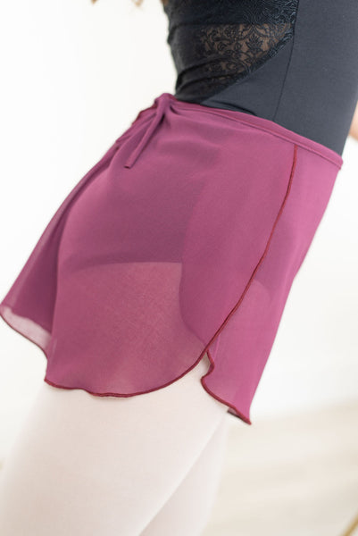 Detail view of a dancer from the side, showing the overlap and waist tie on a pair of Raspberry coloured sheer chiffon shorts.